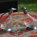 Pair of vintage French glass duck-shaped decanters with pewter mounts and hinged lids.